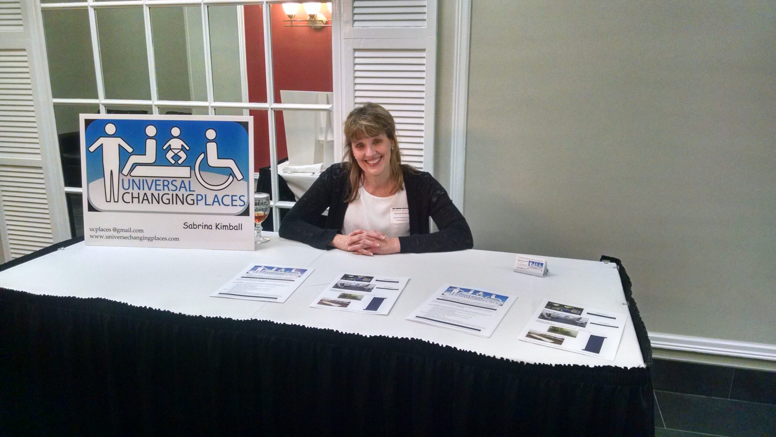 Sabrina Kimball representing Universal Changing Places at an informational exhibit table during the 2017 Jacksonville ADA Conference, sponsored by MaxAbility.